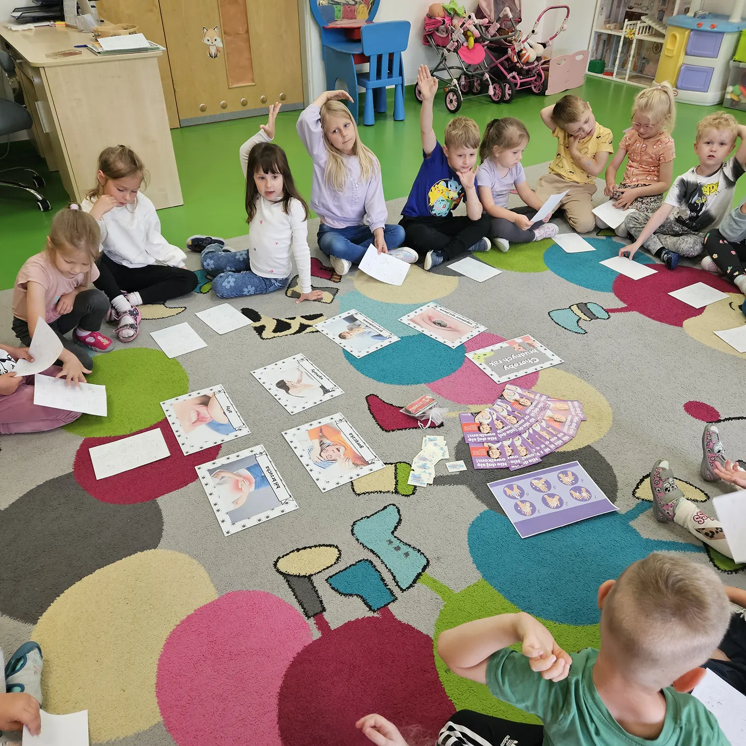  dzieci siedzą na dywanie