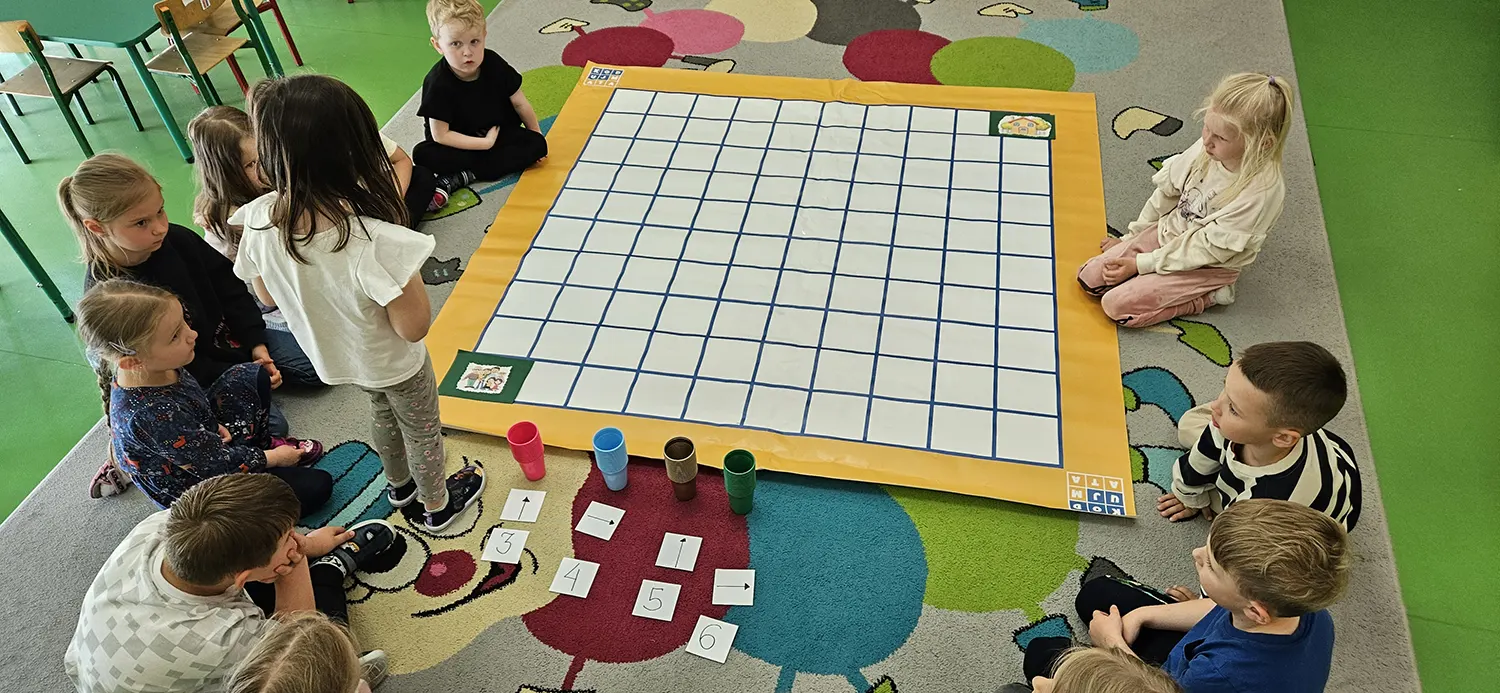  dzieci siedzą na dywanie